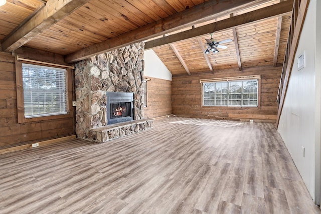 unfurnished living room with ceiling fan, a stone fireplace, wood walls, wood ceiling, and hardwood / wood-style flooring