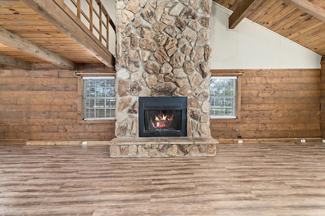 unfurnished living room with a stone fireplace, lofted ceiling with beams, wood walls, wood-type flooring, and wood ceiling