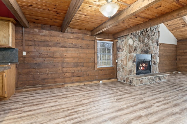 unfurnished living room with beamed ceiling, a fireplace, wood walls, and wood ceiling