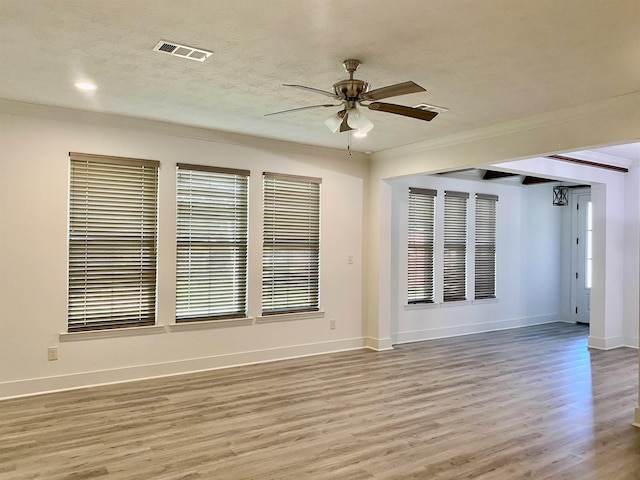 unfurnished room featuring ceiling fan, light wood-type flooring, and ornamental molding