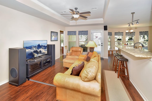 living room with ceiling fan with notable chandelier, sink, crown molding, a tray ceiling, and dark hardwood / wood-style flooring