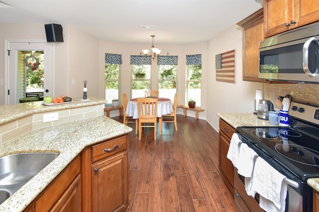 kitchen featuring an inviting chandelier, dark hardwood / wood-style floors, pendant lighting, decorative backsplash, and appliances with stainless steel finishes