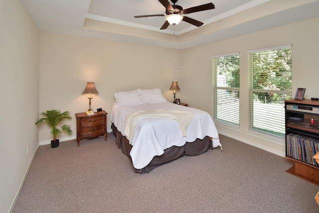 carpeted bedroom with a tray ceiling, ceiling fan, and crown molding