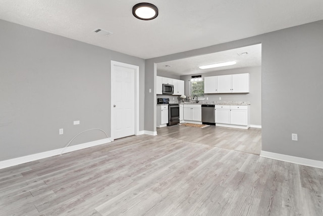 590 Parks St, Silsbee, TX 77656 - unfurnished living room featuring baseboards, light wood-style floors, visible vents, and a sink