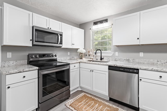 590 Parks St, Silsbee, TX 77656 - kitchen featuring a sink, stainless steel appliances, a textured ceiling, white cabinetry, and light stone countertops