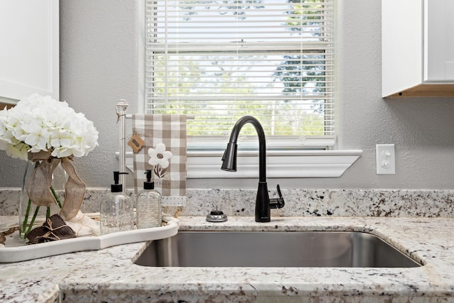 590 Parks St, Silsbee, TX 77656 - interior details featuring white cabinetry, a textured wall, light stone countertops, and a sink
