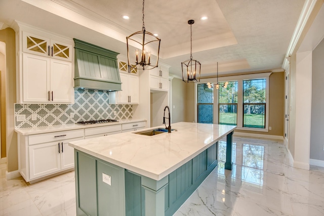 kitchen with marble finish floor, gas cooktop, a raised ceiling, a sink, and custom range hood