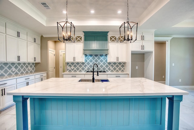 kitchen with a raised ceiling, light stone countertops, a large island, marble finish floor, and an inviting chandelier