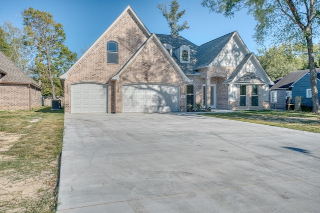 french country inspired facade featuring concrete driveway, central air condition unit, a front yard, brick siding, and a garage