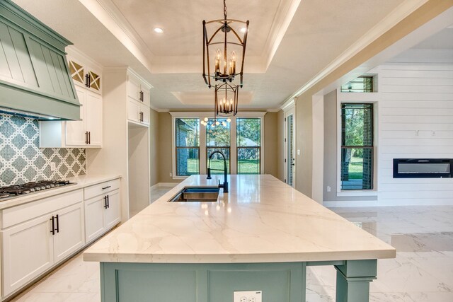 kitchen featuring crown molding, marble finish floor, a raised ceiling, a sink, and an inviting chandelier