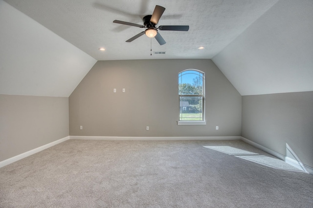 additional living space featuring carpet flooring, a textured ceiling, visible vents, and a ceiling fan
