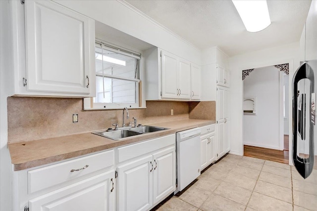 kitchen featuring sink, light tile patterned floors, dishwasher, white cabinetry, and fridge