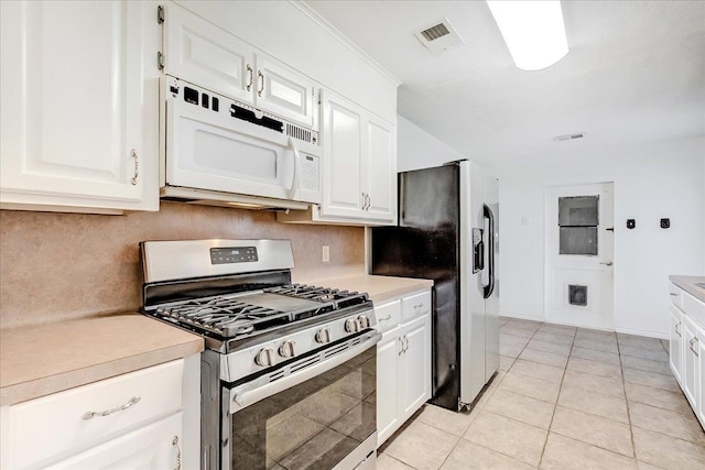 kitchen featuring tasteful backsplash, white cabinetry, light tile patterned flooring, and appliances with stainless steel finishes