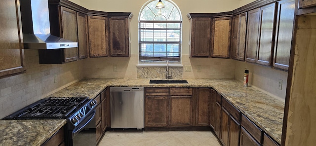 kitchen with light stone countertops, sink, wall chimney exhaust hood, black gas range oven, and stainless steel dishwasher