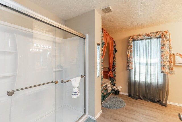 1007 Ewing St, Beaumont, TX 77701 - full bath with wood finished floors, a stall shower, a textured ceiling, and baseboards
