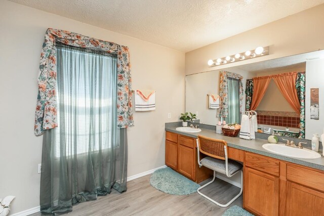 1007 Ewing St, Beaumont, TX 77701 - full bathroom with wood finished floors, double vanity, a textured ceiling, and baseboards