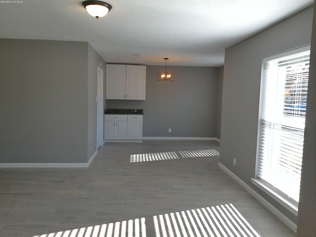 interior space featuring dark wood-type flooring, a textured ceiling, and a notable chandelier