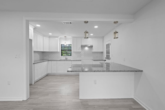 4247 Lansing Ave, Port Arthur, TX 77642 - kitchen with stone countertops, recessed lighting, a peninsula, light wood-type flooring, and white cabinets