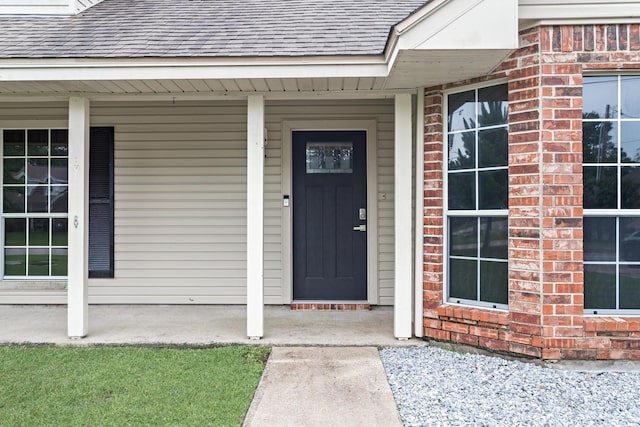 7669 Boardwalk, Lumberton, TX 77657 - doorway to property featuring a shingled roof, covered porch, and brick siding