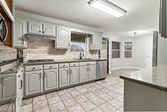 7669 Boardwalk, Lumberton, TX 77657 - kitchen featuring a sink, appliances with stainless steel finishes, under cabinet range hood, backsplash, and dark stone counters