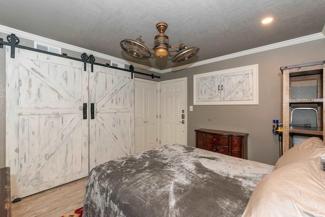 bedroom featuring light hardwood / wood-style floors, ceiling fan, a barn door, and ornamental molding