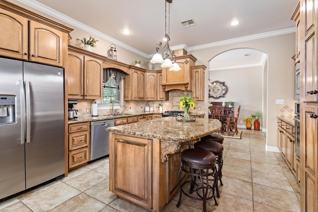 kitchen featuring stainless steel appliances, light stone countertops, sink, and a kitchen island