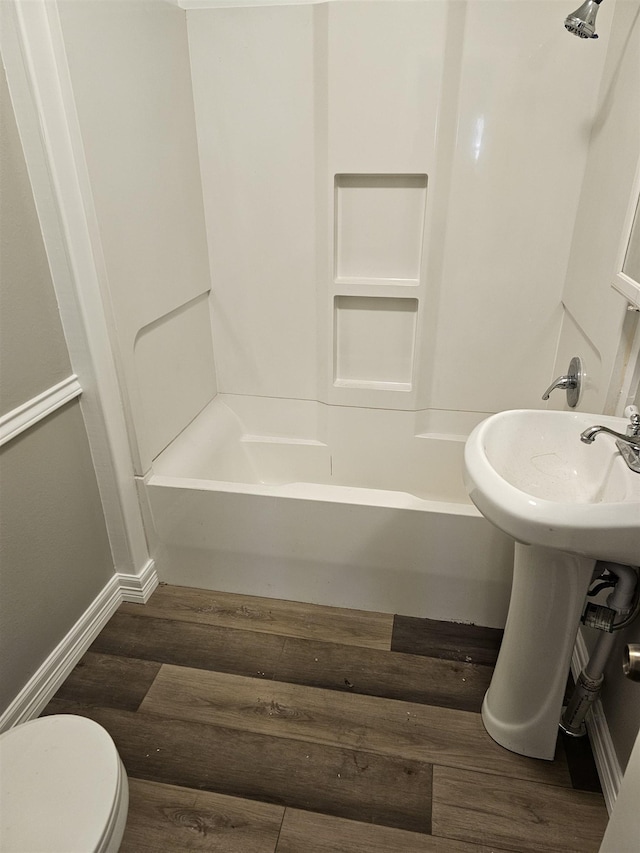 bathroom with hardwood / wood-style flooring, toilet, and bathtub / shower combination