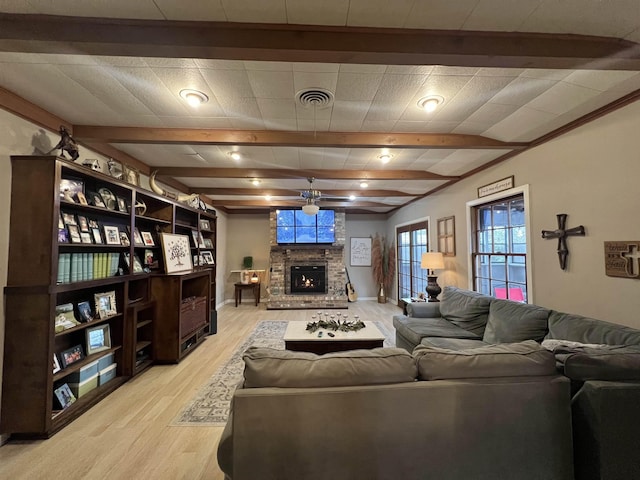 living room with light wood-type flooring, ceiling fan, and a stone fireplace