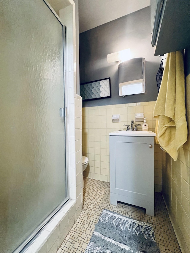 bathroom featuring toilet, a shower with shower door, tile walls, and vanity