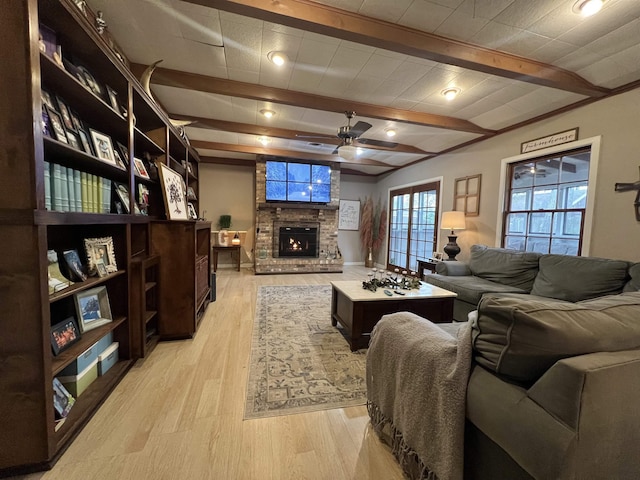 living room featuring a fireplace, ceiling fan, light hardwood / wood-style flooring, and beam ceiling