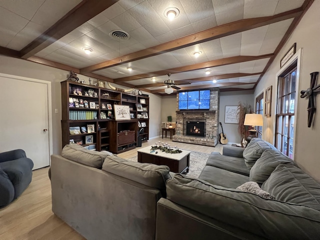 living room featuring a fireplace, ceiling fan, light hardwood / wood-style floors, and beam ceiling