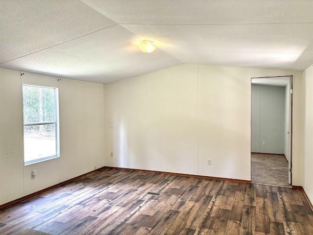 unfurnished room with dark wood-type flooring, a textured ceiling, and lofted ceiling