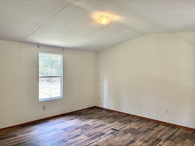 spare room with dark hardwood / wood-style flooring and vaulted ceiling