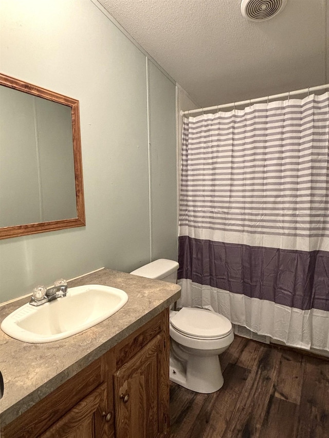 bathroom with a textured ceiling, toilet, hardwood / wood-style flooring, and vanity