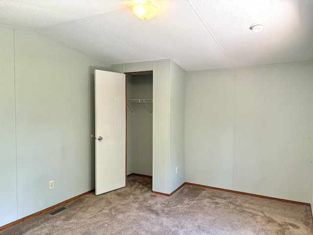 unfurnished bedroom with light colored carpet, a closet, and lofted ceiling