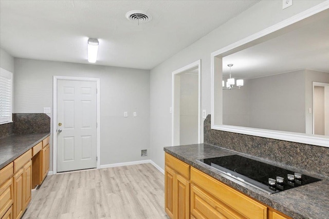 kitchen featuring black electric stovetop, light wood-type flooring, hanging light fixtures, and a chandelier