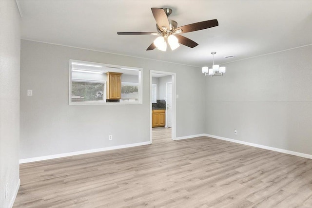 empty room featuring ceiling fan with notable chandelier and light hardwood / wood-style floors