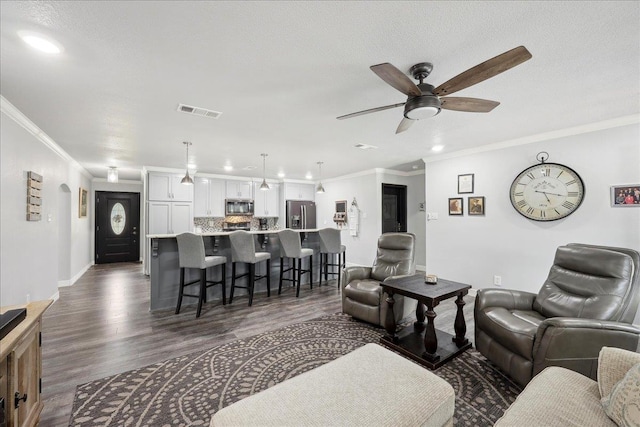 living area with visible vents, baseboards, ceiling fan, dark wood finished floors, and ornamental molding