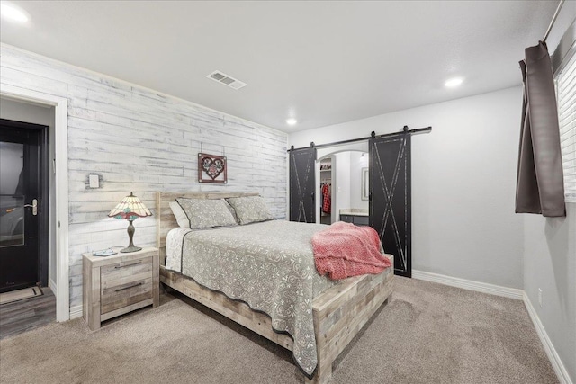 bedroom featuring a spacious closet, visible vents, carpet, and a barn door