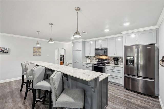 kitchen with visible vents, arched walkways, decorative backsplash, appliances with stainless steel finishes, and crown molding