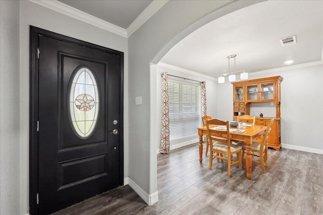 entryway with crown molding, wood finished floors, visible vents, and arched walkways