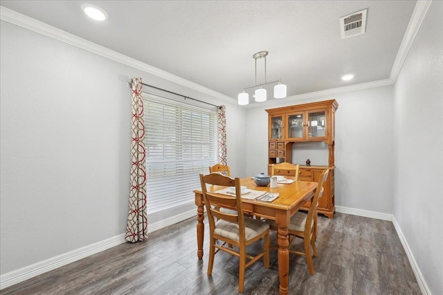 dining space featuring visible vents, baseboards, dark wood finished floors, and crown molding