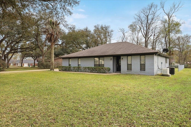 view of front of house featuring a front lawn, central air condition unit, and brick siding