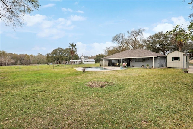 view of yard with an outbuilding, an outdoor pool, concrete driveway, a storage unit, and a patio area