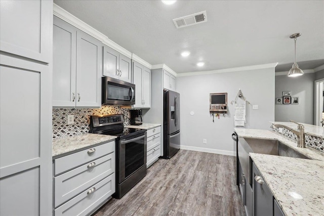 kitchen with visible vents, ornamental molding, wood finished floors, appliances with stainless steel finishes, and decorative backsplash