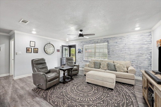 living room with visible vents, a textured ceiling, wood finished floors, and ornamental molding