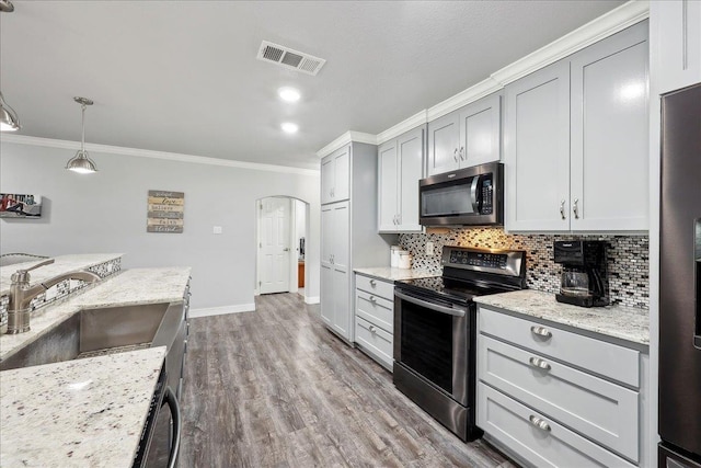 kitchen with visible vents, a sink, backsplash, arched walkways, and appliances with stainless steel finishes