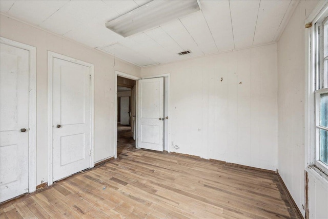 unfurnished bedroom with visible vents, light wood finished floors, and baseboards