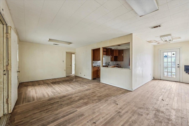 unfurnished living room featuring visible vents and wood finished floors