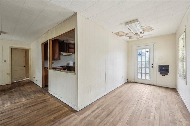 unfurnished room with baseboards, wood walls, and wood finished floors